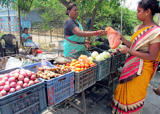 Eine Frau verkauft einer anderen Frau Obst und Gemüse